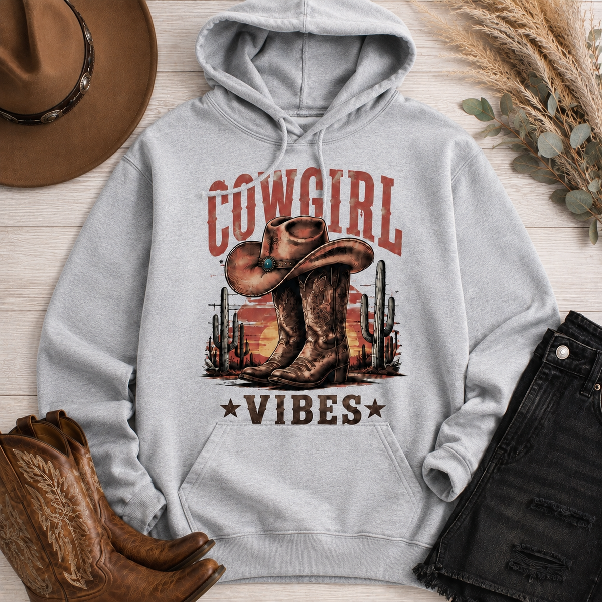 Cowgirl Vibes western graphic apparel featuring cowboy boots, cowgirl hat, cacti and desert sunset design