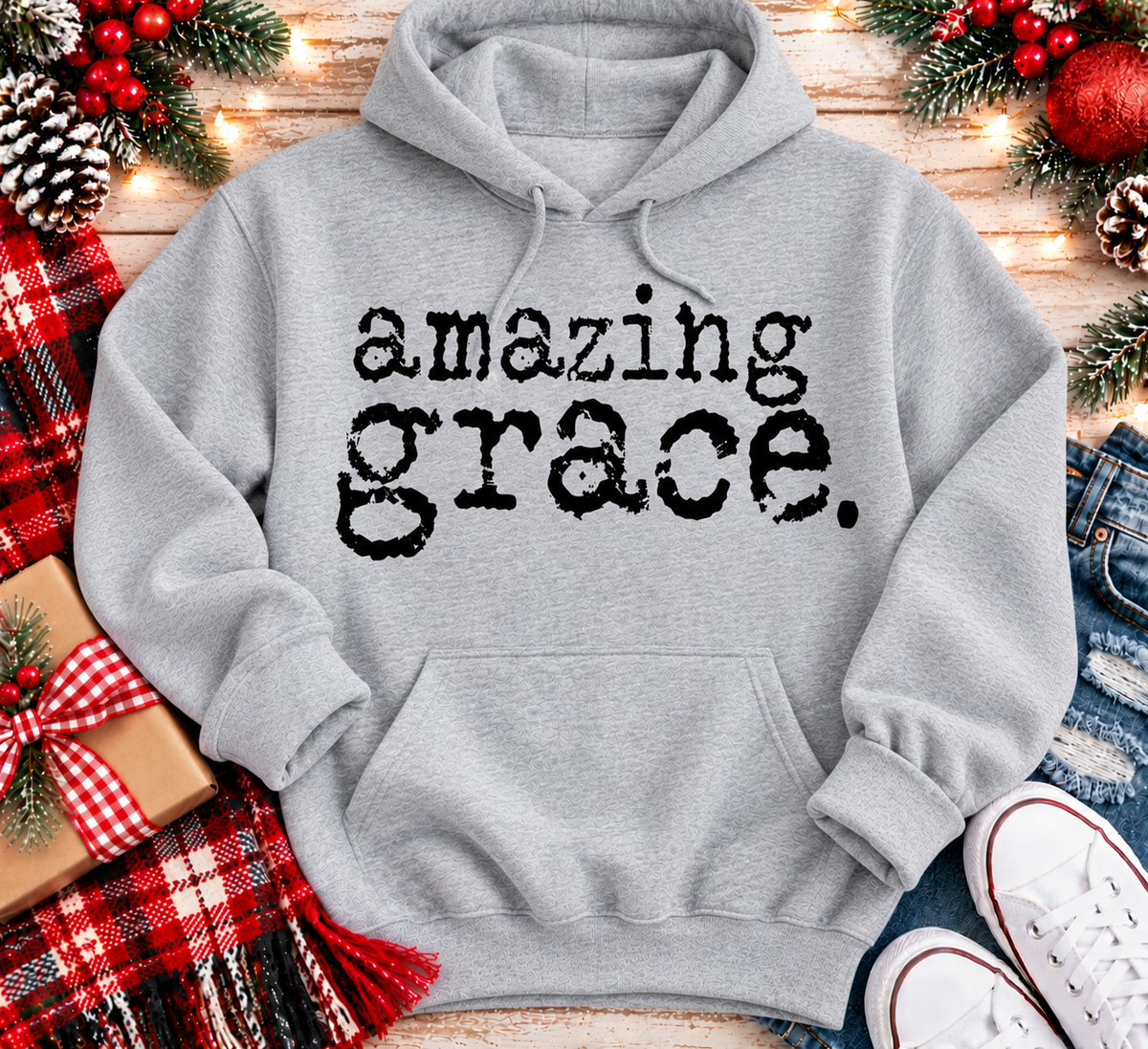 A light gray pullover hoodie with the words 'amazing grace.' printed in a black typewriter-style font across the chest.