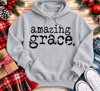 A light gray pullover hoodie with the words 'amazing grace.' printed in a black typewriter-style font across the chest.