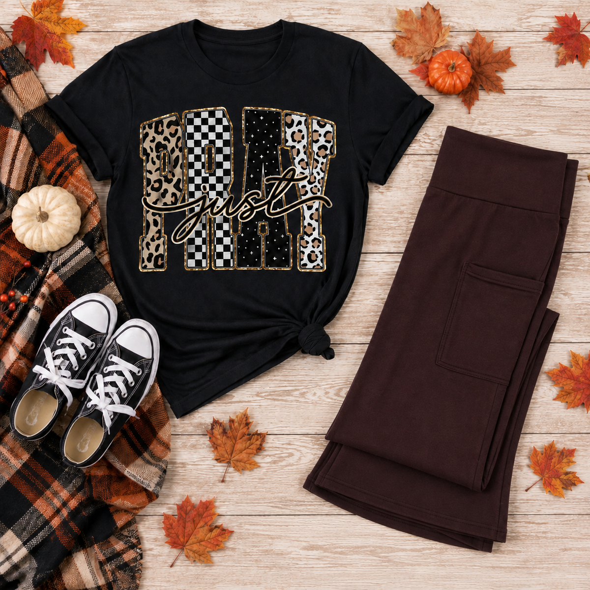 Black Pray Just Pray graphic T-shirt with leopard, cow print, checkerboard, and star lettering styled with brown leggings and fall accessories.