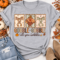 Gobble Gobble Till You Wobble Thanksgiving graphic apparel featuring a cute turkey, polka dot bows, retro fall colors, pumpkins and autumn leaves.