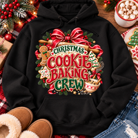 A black pullover hoodie laid flat with a large festive Christmas cookie baking graphic on the front. The design includes red bows, green pine branches, gingerbread cookies, mixing bowls, and the words “Christmas Cookie Baking Crew.