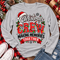Christmas Crew Making Memories Together graphic on a pink crewneck T-shirt, featuring red lettering, colorful Christmas lights, a Santa hat, holly, and snowflakes.