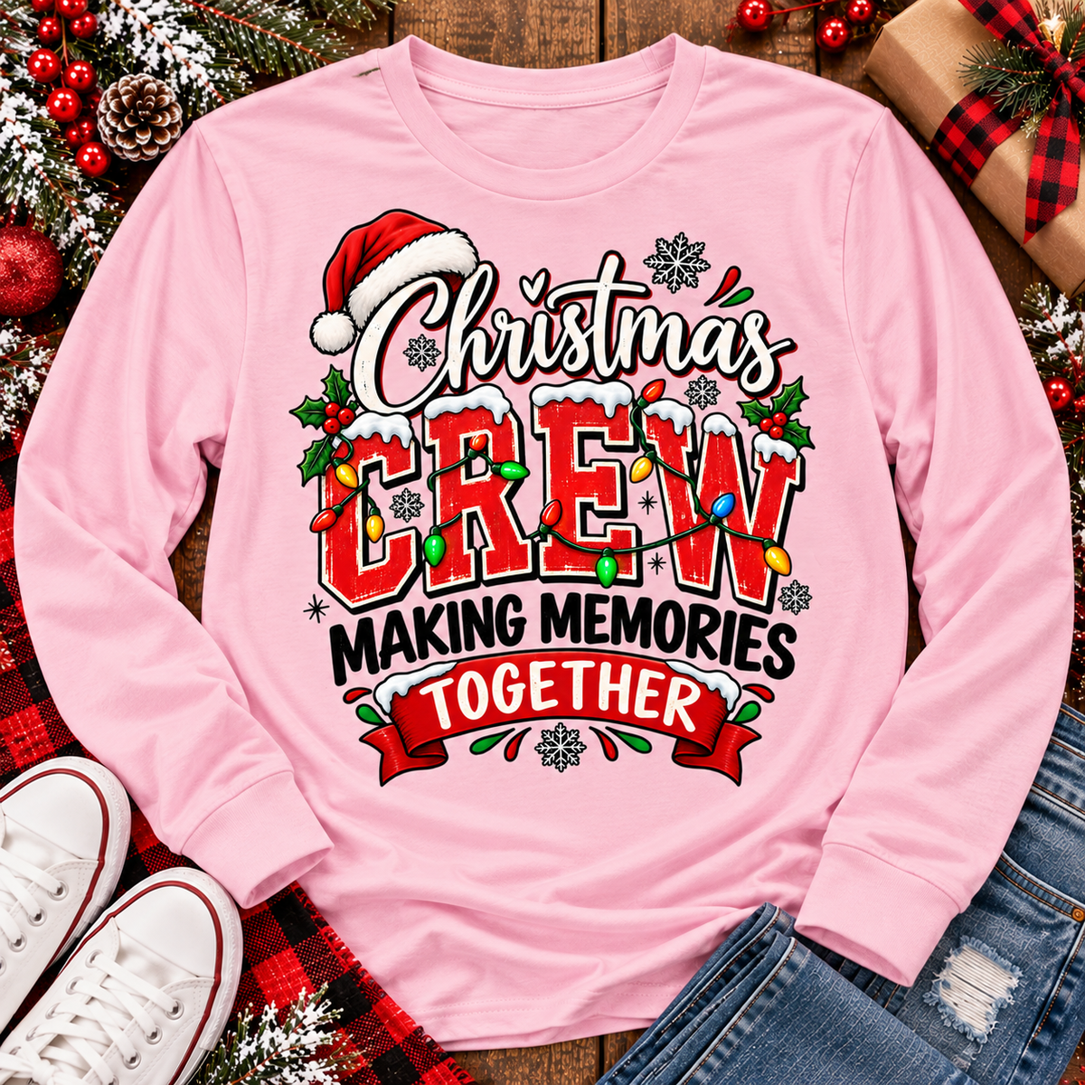 Christmas Crew Making Memories Together graphic on a pink crewneck T-shirt, featuring red lettering, colorful Christmas lights, a Santa hat, holly, and snowflakes.