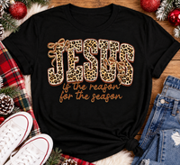Jesus Is the Reason for the Season Christmas graphic shirt featuring bold leopard print JESUS lettering, decorative gold bows, and gold script. Faith-inspired holiday apparel available in red and black with four style options.