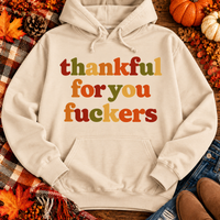 Funny Thankful for You Fuckers Thanksgiving graphic tee featuring bold retro lettering in burnt orange, mustard yellow, olive green, and rust red. Women's fall-inspired short sleeve crewneck shirt available in beige and brown, perfect for Thanksgiving and Friendsgiving.