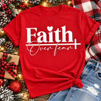 Faith Over Fear Christian inspirational graphic apparel featuring bold white Faith lettering, elegant Over Fear script, a small heart, and a cross design. Available in red and black in short sleeve crewneck, long sleeve crewneck, crewneck sweatshirt, and hoodie styles. Faith-based graphic clothing for women, everyday wear, church outfits, and inspirational gifts.