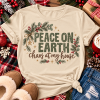 Peace on Earth Chaos at My House funny Christmas graphic apparel featuring distressed olive green lettering, rustic pine greenery, red berries and gold stars, available in sand and sport grey in short sleeve crewneck tees, V-neck tees, sweatshirts and hoodies.