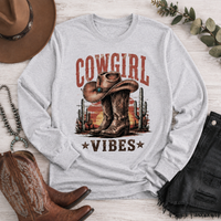 Cowgirl Vibes western graphic apparel featuring cowboy boots, cowgirl hat, cacti and desert sunset design