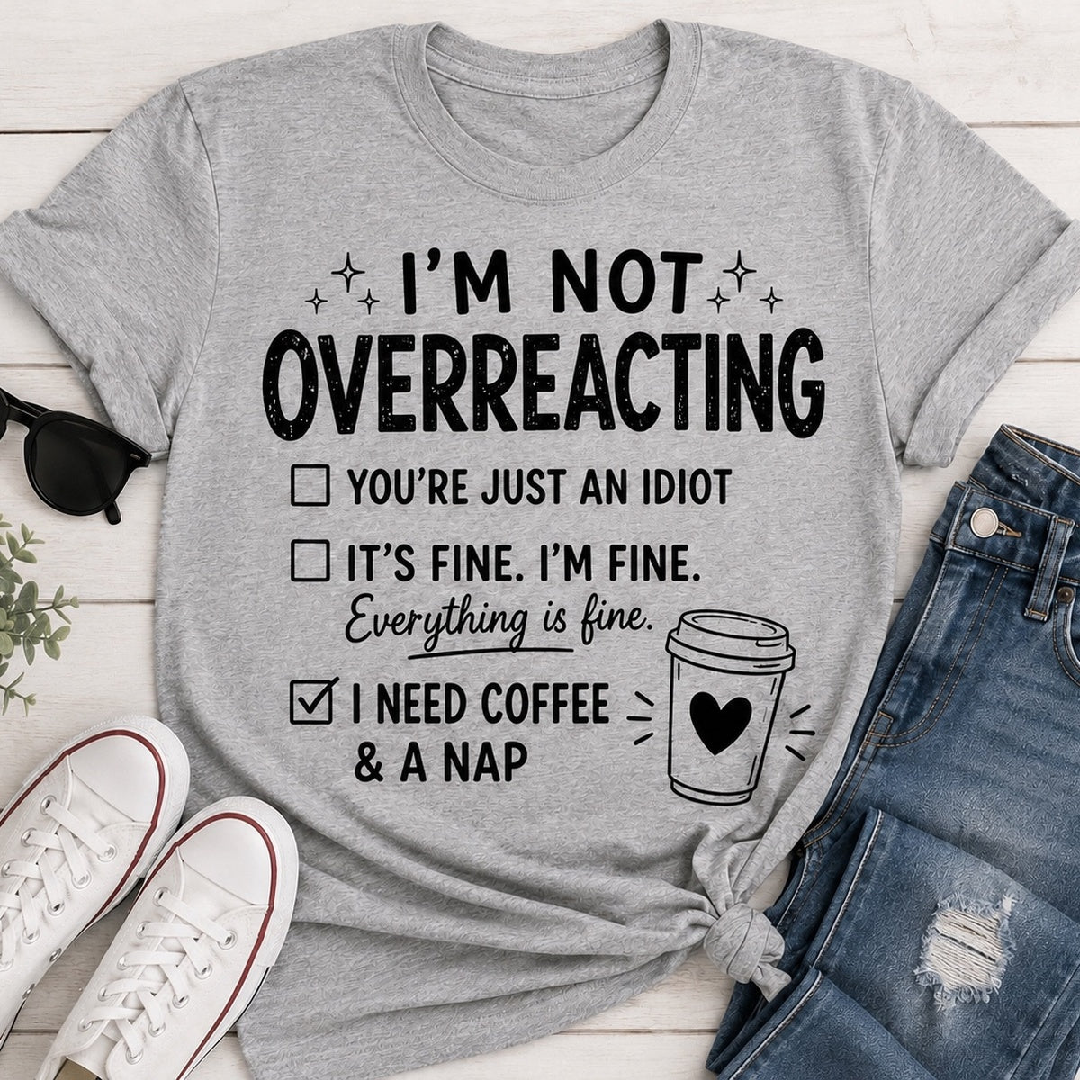 Gray I’m Not Overreacting graphic T-shirt featuring funny checklist sayings, black lettering, coffee cup graphic and I Need Coffee and a Nap text.