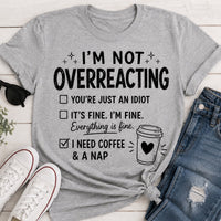 Gray I’m Not Overreacting graphic T-shirt featuring funny checklist sayings, black lettering, coffee cup graphic and I Need Coffee and a Nap text.