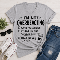Gray I’m Not Overreacting graphic T-shirt featuring funny checklist sayings, black lettering, coffee cup graphic and I Need Coffee and a Nap text.
