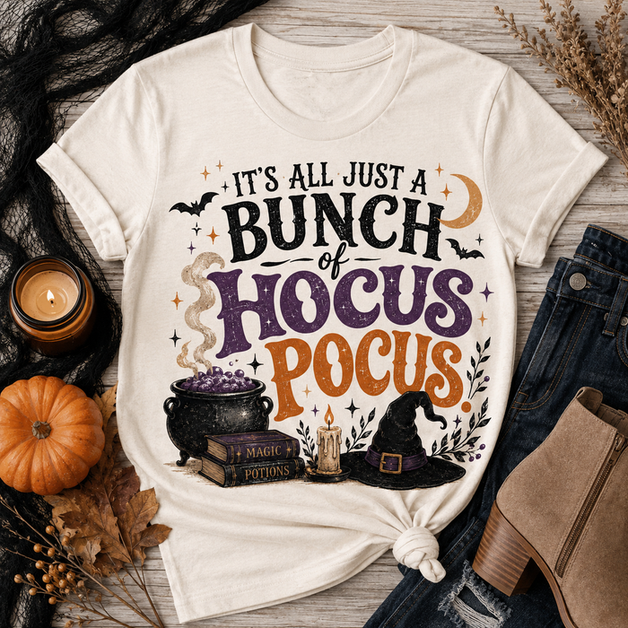 Beige Halloween graphic tee with It’s All Just a Bunch of Hocus Pocus lettering, cauldron, spell books, witch hat and bats.