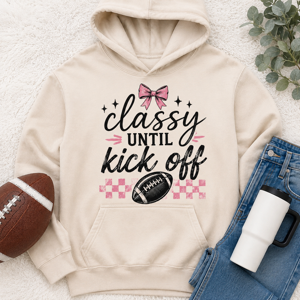 Cream Classy Until Kickoff football hoodie featuring a pink bow, black football, pink checkerboard pattern and black and pink game day lettering.