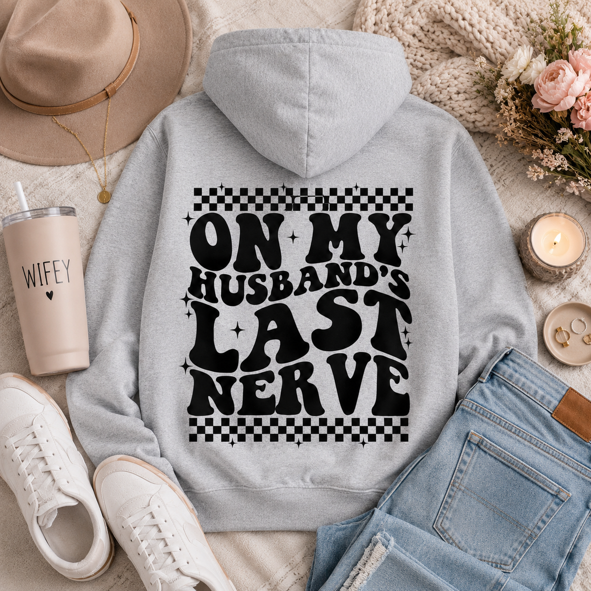 Gray graphic hoodie featuring bold black “On My Husband’s Last Nerve” lettering with checkerboard and sparkle details on the back.